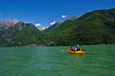 Friends kayaking on river against mountains at novate mezzola