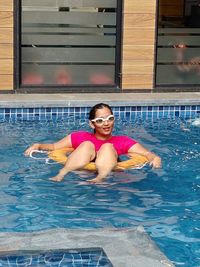 Portrait of smiling young woman swimming in pool