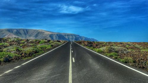Road leading towards mountain against sky