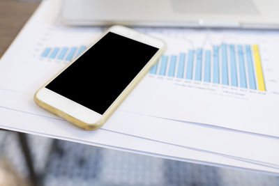 Close-up of smart phone with graph on table