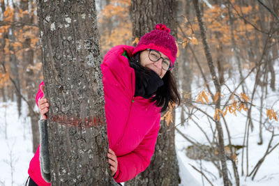 In the snowy forest, a woman dressed in mountain clothes, smiles happily in nature.