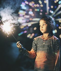 Girl holding illuminated sparkler at night
