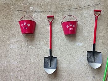 Red bucket with shovels hanging on wall