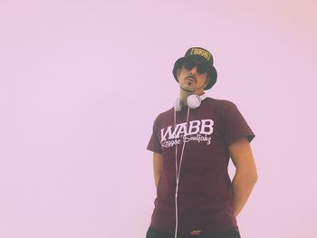 Portrait of man standing against wall against clear sky