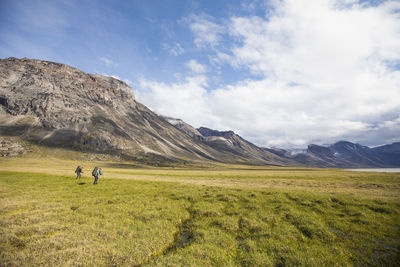 Backpackers hiking in akshayak pass, auyuittuq national park.