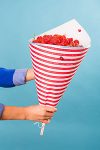 Cropped hand of woman holding food against blue background