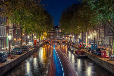 Illuminated bridge over canal in city at night