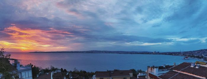 Panoramic view of sea and buildings against sky at sunset