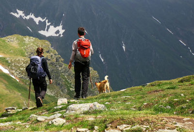 Rear view of hikers with dog standing on mountain