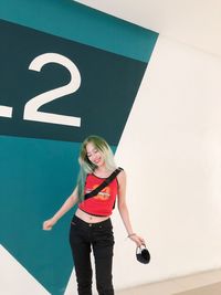 Portrait of young woman standing against wall