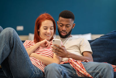 Guy and girl hug using phone. woman and man watching videos, news from smartphone, smiling, laughing