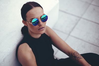 High angle portrait of woman wearing sunglasses by wall