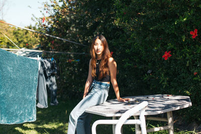 Portrait of young woman against plants in backyard