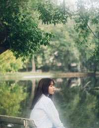 Portrait of young woman standing against trees