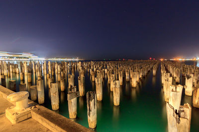 Panoramic view of wooden posts in sea against sky at night