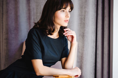 Beautiful young woman sitting on chair at home