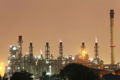 Illuminated factory against sky at night