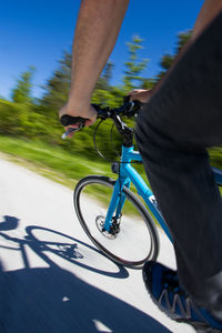 Low section of man riding bicycle on road