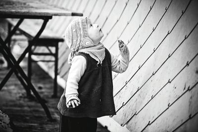 Baby girl looking up while standing by wall