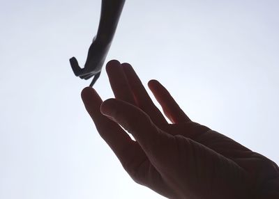 Cropped hand of person touching statue against sky