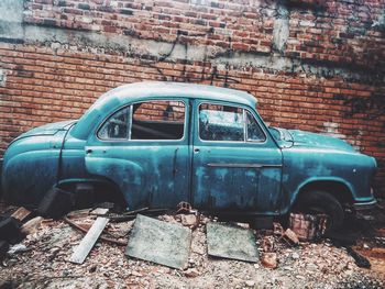 Abandoned car against brick wall