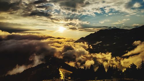 Scenic view of dramatic sky over silhouette mountains during sunset