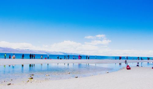 People at beach against blue sky