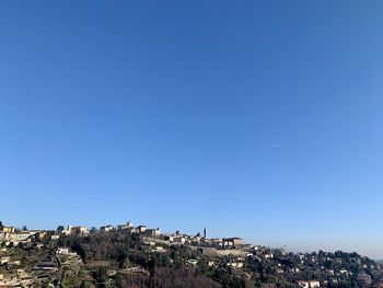 Buildings in city against clear blue sky