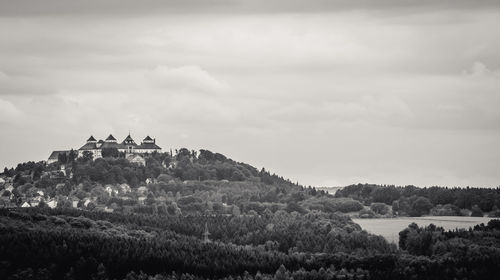 House on landscape against cloudy sky