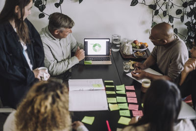 Male fashion designer conducting meeting with colleagues on laptop at workshop