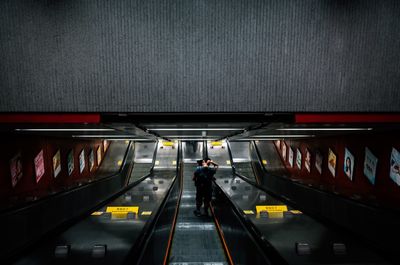 Rear view of man standing on escalator in subway station