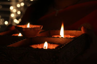 Close-up of lit diyas in box