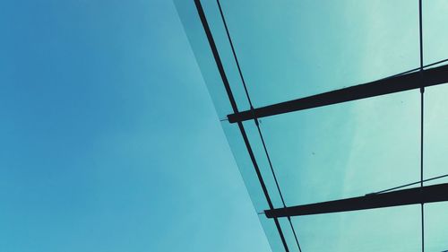 Low angle view of power lines against clear blue sky