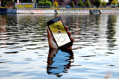 Woman holding mobile phone in lake