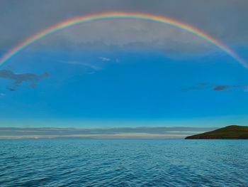 Scenic view of rainbow over sea against sky