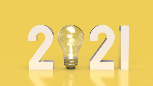 Close-up of illuminated light bulb against yellow background