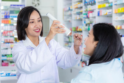 Asian female doctor examining throat of patient with flashlight. health care and treatment