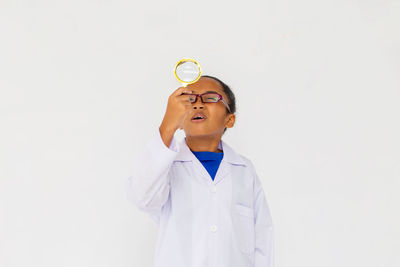 Girl looking away while standing against white background