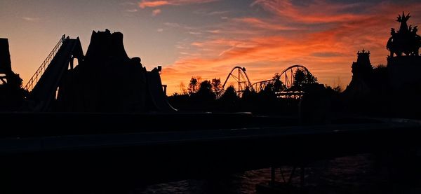 Silhouette of city against cloudy sky during sunset