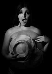 Portrait of woman standing against black background