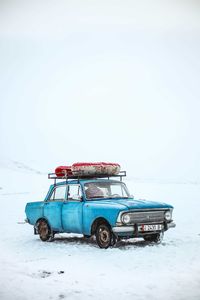 Car parked on snow field against sky