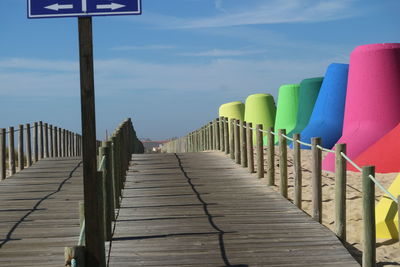 Empty footpath by railing against sky