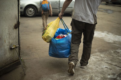 Man carrying blue bag. moving with things. guy dragging things. person shoots things in car. person