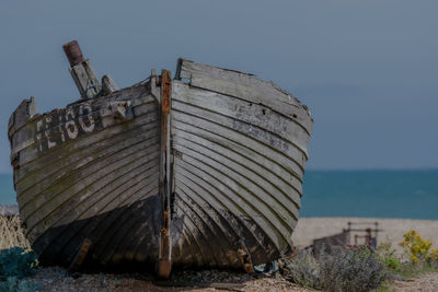 Abandoned boat on beach against sky