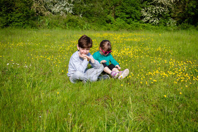 Rear view of friends sitting on grassy field