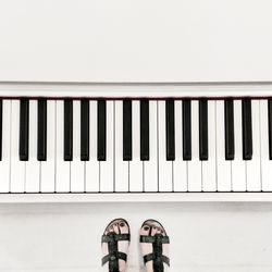 Low section view of woman standing by piano