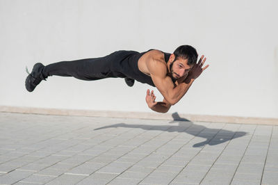 Low angle view of man exercising on footpath