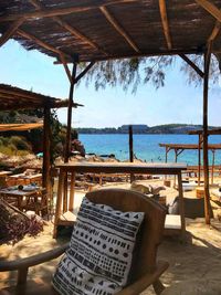 Chairs and table at beach against sky