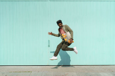 Full length of young man jumping against wall