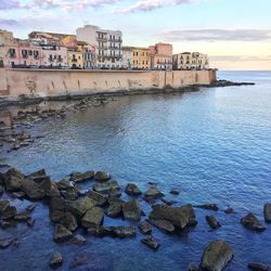 Scenic view of sea by buildings against sky